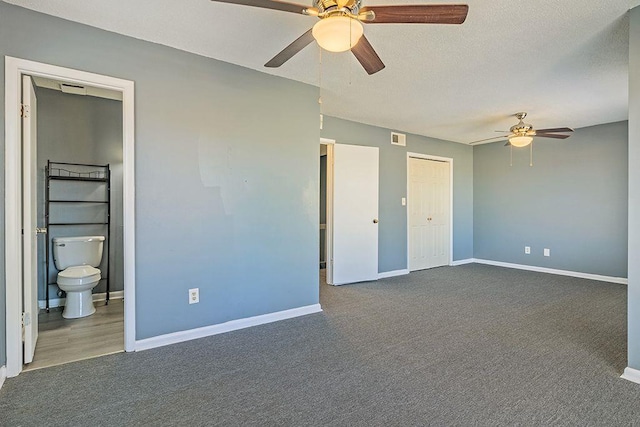 unfurnished bedroom featuring dark colored carpet, connected bathroom, and ceiling fan