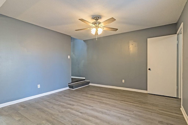 empty room featuring ceiling fan, wood-type flooring, and a textured ceiling