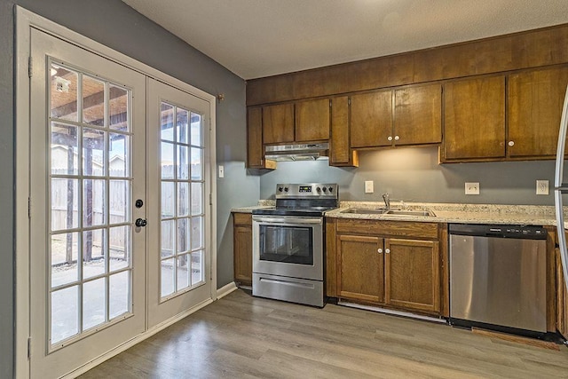 kitchen with french doors, stainless steel appliances, light hardwood / wood-style floors, and sink