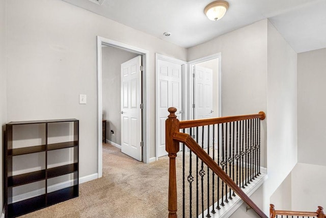 hallway featuring baseboards, light colored carpet, and an upstairs landing