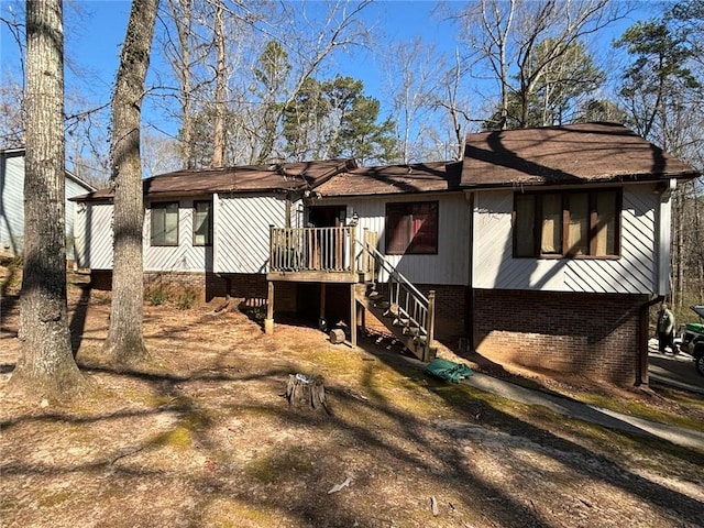 view of front of house featuring a wooden deck, stairway, and brick siding