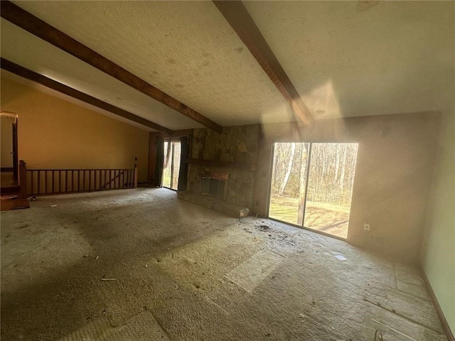 unfurnished living room featuring vaulted ceiling with beams, a textured ceiling, and a stone fireplace