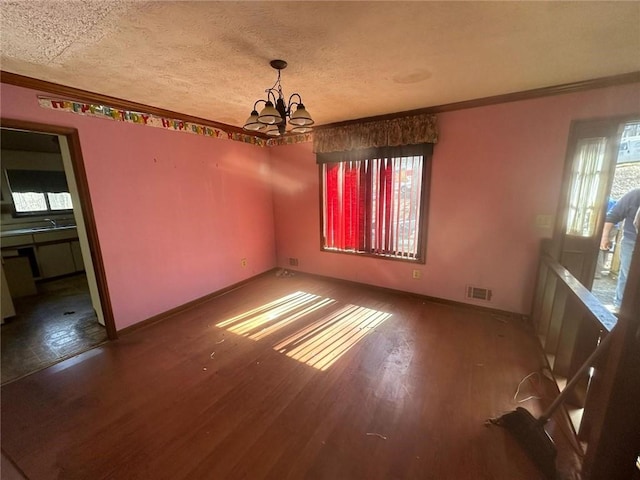 unfurnished dining area with a textured ceiling, wood finished floors, visible vents, and crown molding