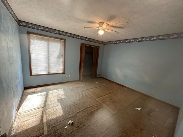 empty room featuring a textured ceiling, a ceiling fan, and baseboards