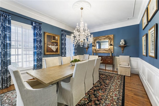 dining room featuring plenty of natural light, wood finished floors, wainscoting, and a chandelier