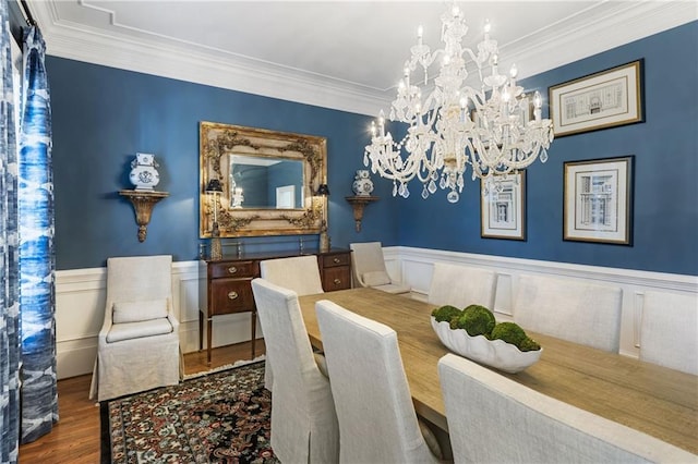 dining area with crown molding, wood finished floors, a wainscoted wall, and a chandelier