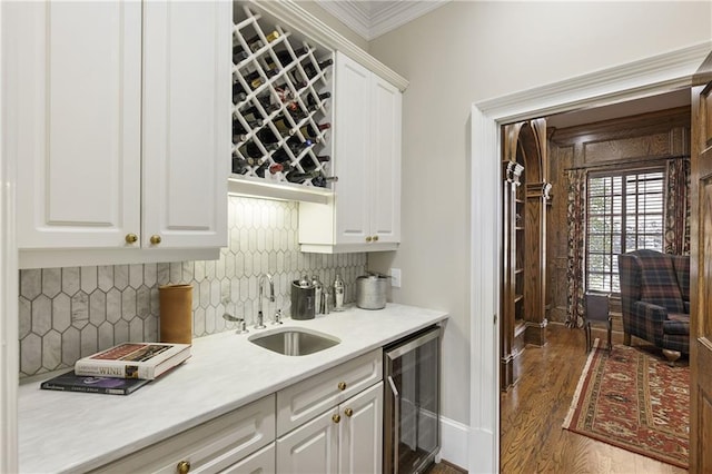 bar featuring beverage cooler, ornamental molding, a sink, tasteful backsplash, and dark wood-style flooring