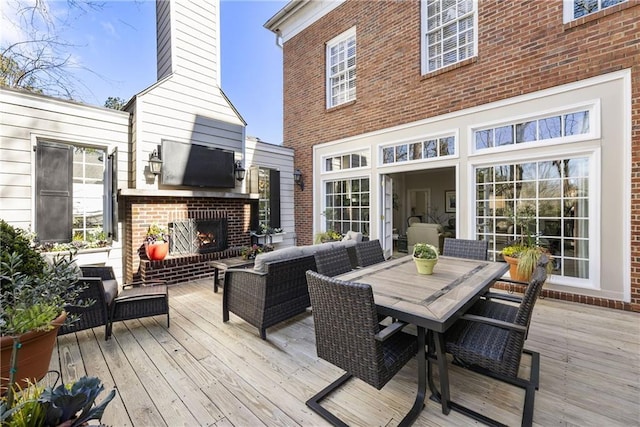 deck with an outdoor living space with a fireplace and outdoor dining area