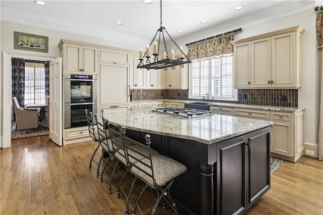 kitchen featuring light wood-type flooring, stainless steel appliances, cream cabinetry, and a center island