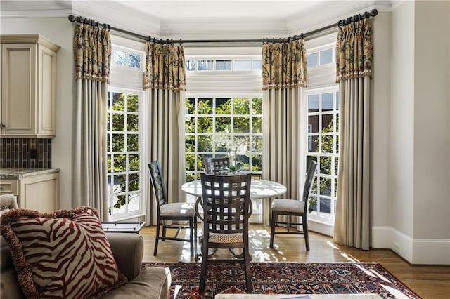 dining space with light wood-type flooring, baseboards, and ornamental molding