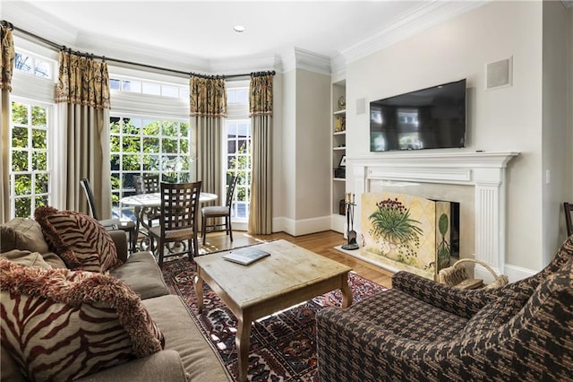 living room with built in features, baseboards, wood finished floors, and crown molding