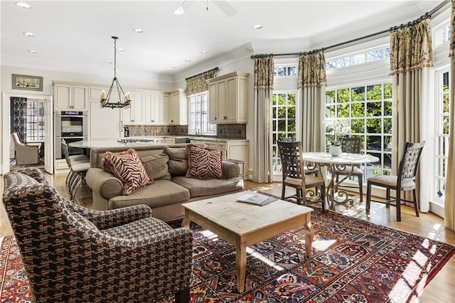 living area featuring a chandelier, recessed lighting, light wood finished floors, and ornamental molding