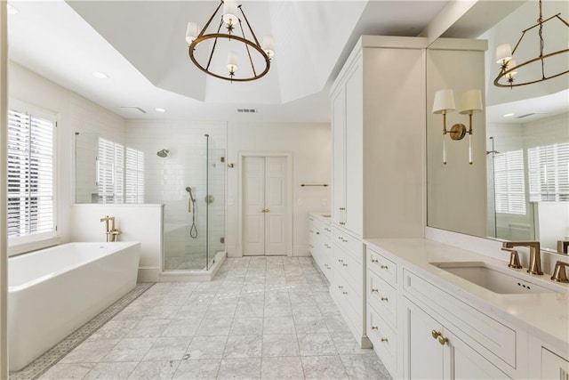 bathroom featuring a shower stall, a tray ceiling, an inviting chandelier, a soaking tub, and vanity