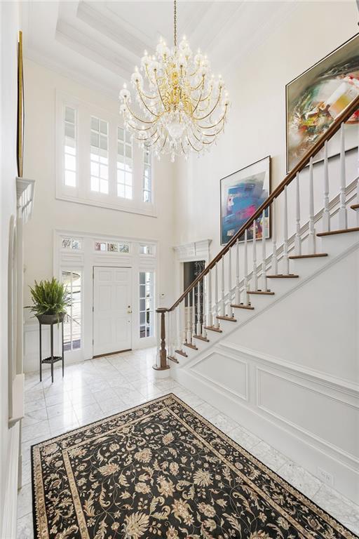 foyer featuring a decorative wall, stairway, crown molding, and a wainscoted wall