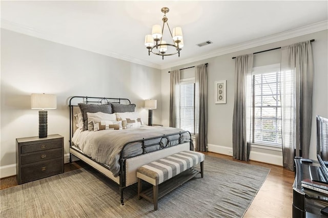 bedroom with a notable chandelier, visible vents, crown molding, and wood finished floors