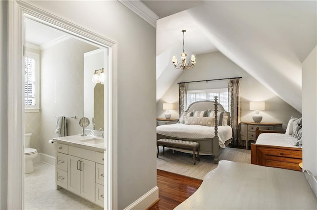 bedroom featuring a sink, ensuite bath, vaulted ceiling, and ornamental molding