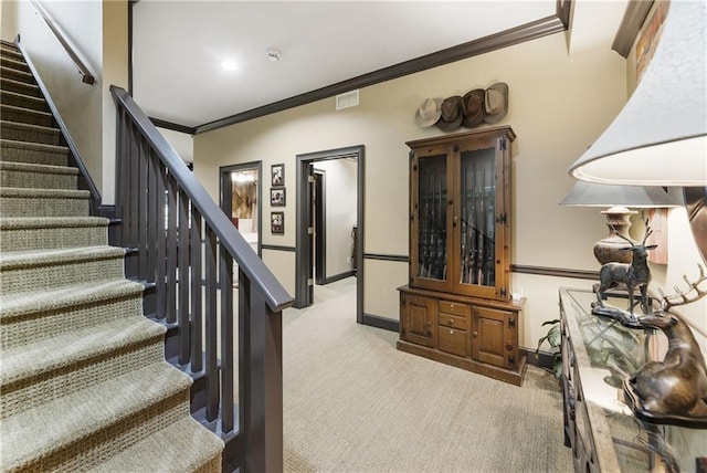 stairway featuring visible vents, baseboards, ornamental molding, and carpet flooring