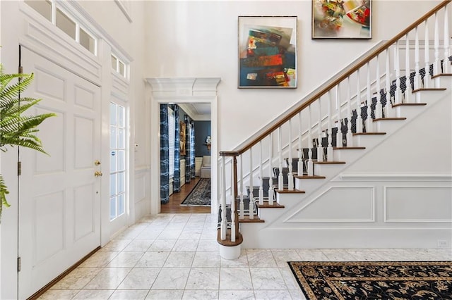 foyer featuring a decorative wall, stairs, and a high ceiling