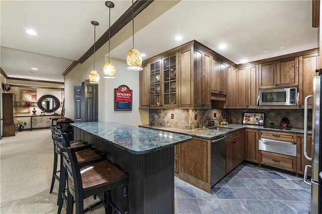 kitchen featuring dark stone counters, glass insert cabinets, appliances with stainless steel finishes, a warming drawer, and backsplash