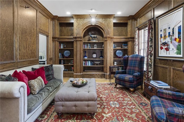 sitting room featuring wooden walls, wood finished floors, a decorative wall, and built in features