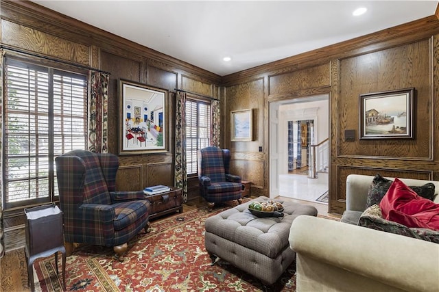 sitting room featuring wooden walls, stairs, and ornamental molding