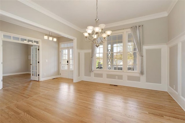 empty room with visible vents, crown molding, a chandelier, light wood-type flooring, and french doors