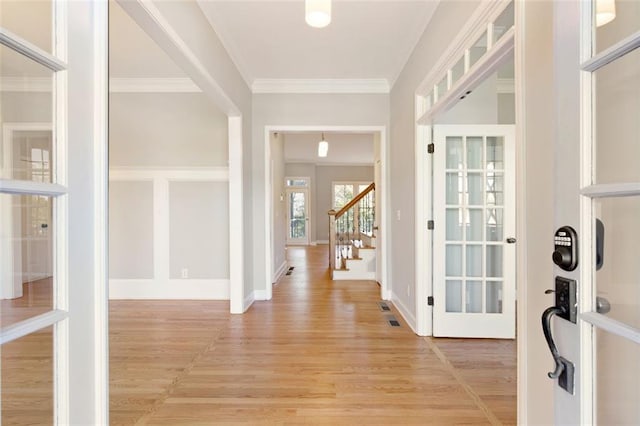 foyer featuring crown molding, stairs, light wood-type flooring, and baseboards