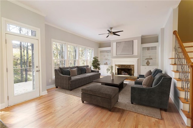 living room with stairs, crown molding, light wood-style floors, and a healthy amount of sunlight