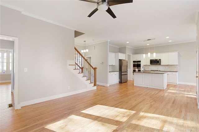 unfurnished living room featuring a sink, baseboards, stairs, and light wood finished floors