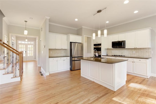 kitchen with dark countertops, light wood-style flooring, stainless steel appliances, and a sink