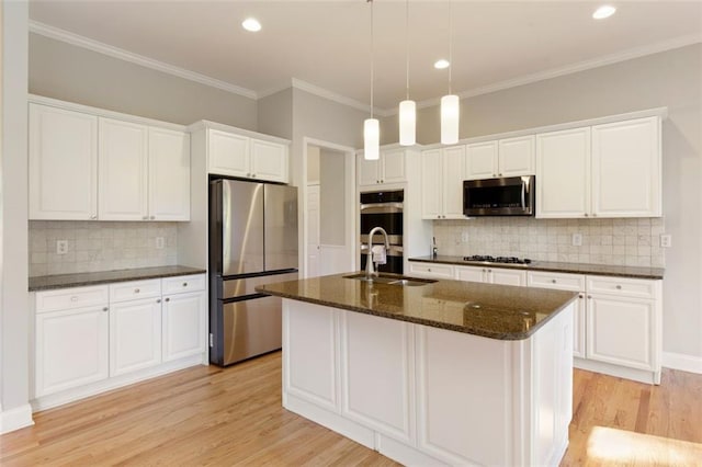 kitchen featuring a center island with sink, light wood-style flooring, a sink, appliances with stainless steel finishes, and crown molding