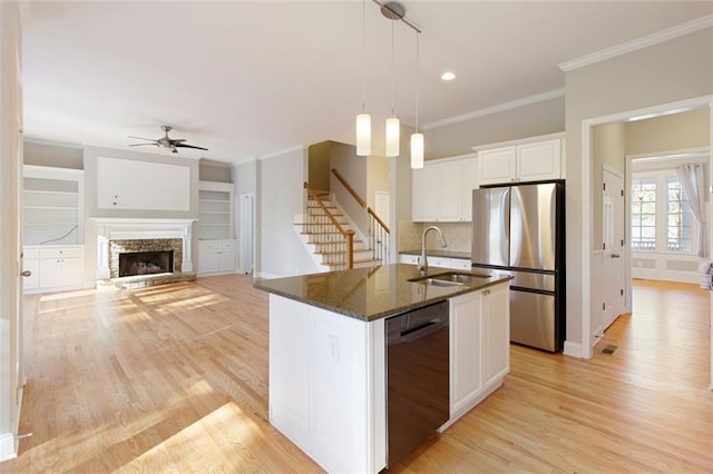 kitchen with dark stone countertops, freestanding refrigerator, ornamental molding, a sink, and black dishwasher