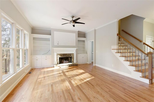 unfurnished living room featuring stairs, light wood-style flooring, baseboards, and ornamental molding