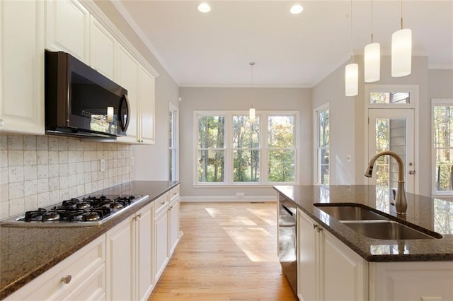 kitchen featuring ornamental molding, light wood-style flooring, a sink, stainless steel appliances, and decorative backsplash