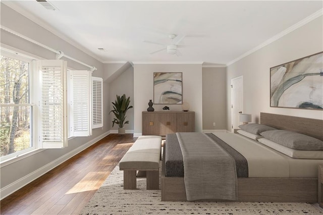 bedroom featuring visible vents, ornamental molding, a ceiling fan, wood finished floors, and baseboards