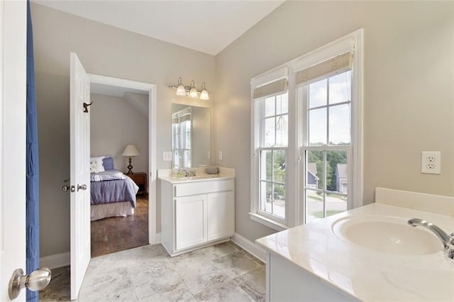 ensuite bathroom featuring two vanities, baseboards, ensuite bathroom, and a sink