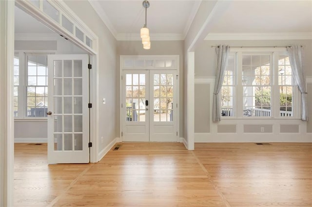 foyer entrance with crown molding, french doors, and light wood-type flooring