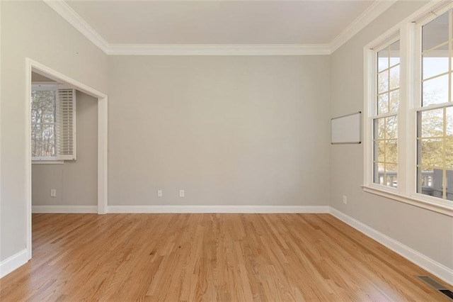 empty room with light wood-style floors, visible vents, a wealth of natural light, and ornamental molding