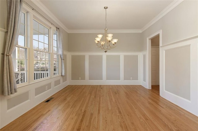 unfurnished dining area with a chandelier, a decorative wall, light wood finished floors, and visible vents