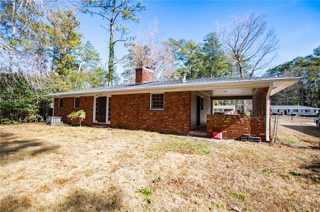 rear view of house with cooling unit and a yard