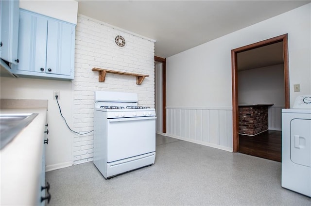 kitchen with brick wall, washer / dryer, white range with gas stovetop, and white cabinets