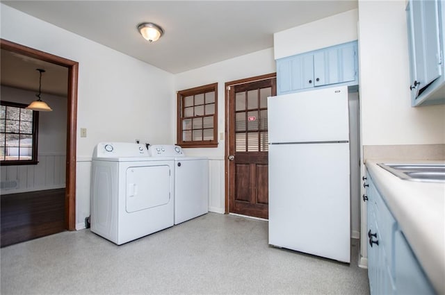 laundry area with cabinets, washing machine and dryer, and sink