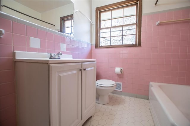 bathroom with vanity, toilet, tile patterned flooring, and tile walls