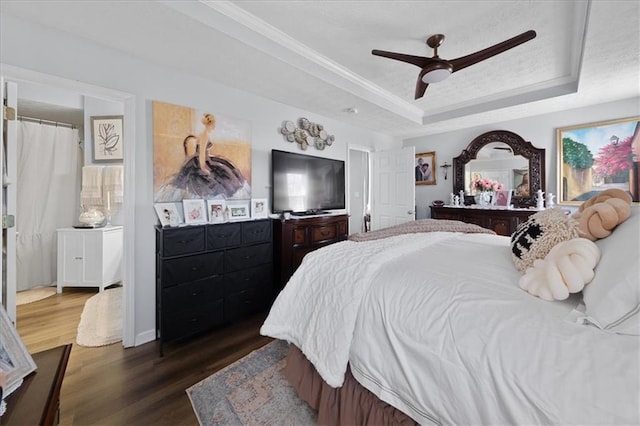 bedroom featuring dark wood-style floors, ceiling fan, a tray ceiling, and crown molding