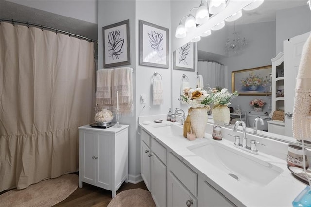 bathroom featuring double vanity, a notable chandelier, a sink, and wood finished floors