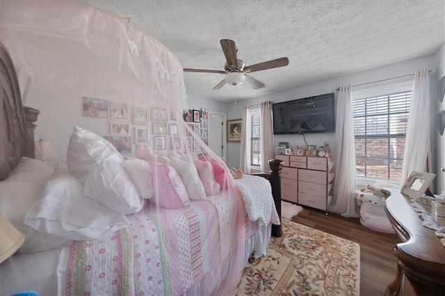 bedroom with a textured ceiling, dark wood-type flooring, and a ceiling fan