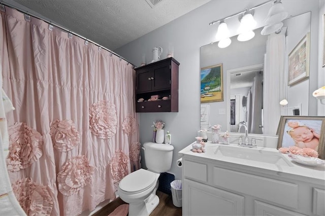 full bathroom featuring toilet, a textured ceiling, and vanity