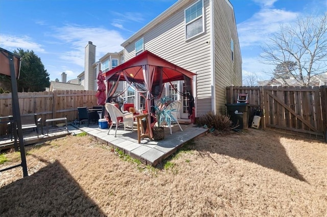 rear view of property with a patio area, a fenced backyard, and a gazebo