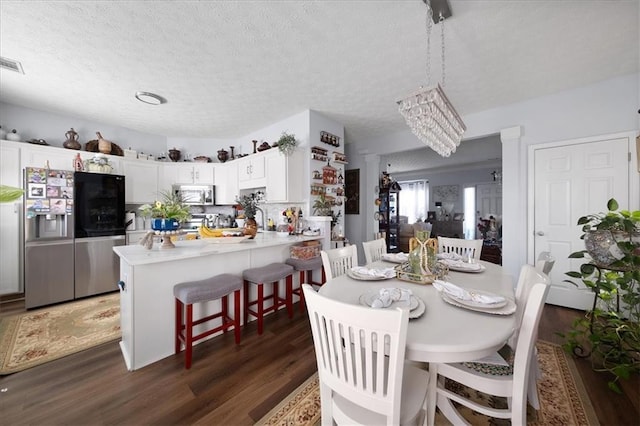 dining room with a textured ceiling, dark wood-type flooring, and visible vents