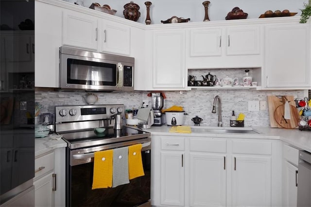 kitchen with tasteful backsplash, white cabinets, stainless steel appliances, light countertops, and a sink